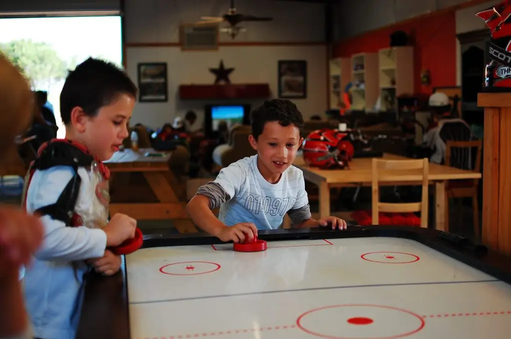 Two boys playing Air Hockey in Rec Center of Iron Horse Country Motocross Summer Camp