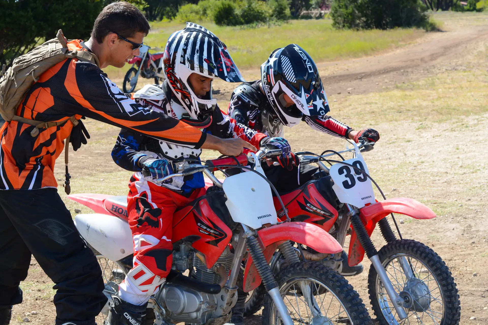 Coach instructing two Iron Horse Country Motocross Summer campers how to ride Honda CRF 80 100 125 150 dirt bikes