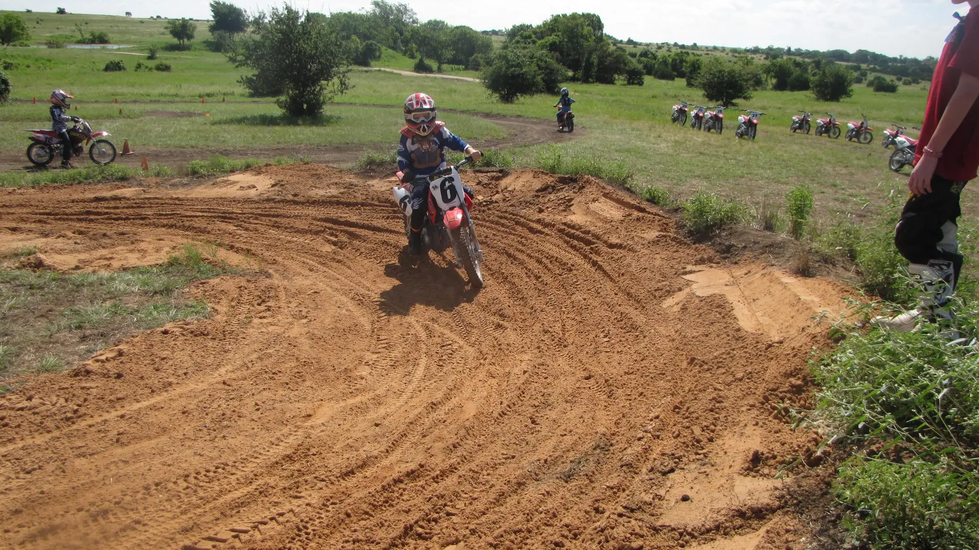 Motocross summer camp rider turning on dirt track at Iron Horse Country Ranch with Honda motorcycles in background
