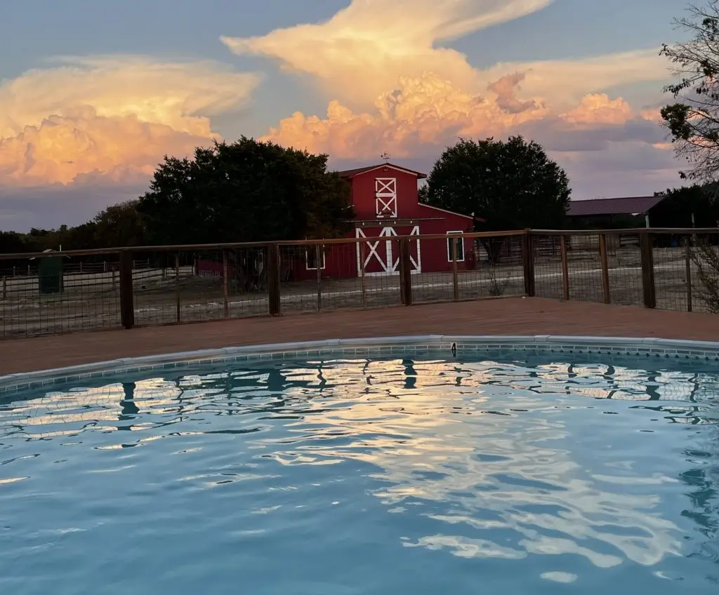 Pool with Red Barn and big sky with clouds at Iron Horse Country Ranch Summer Motocross Camp