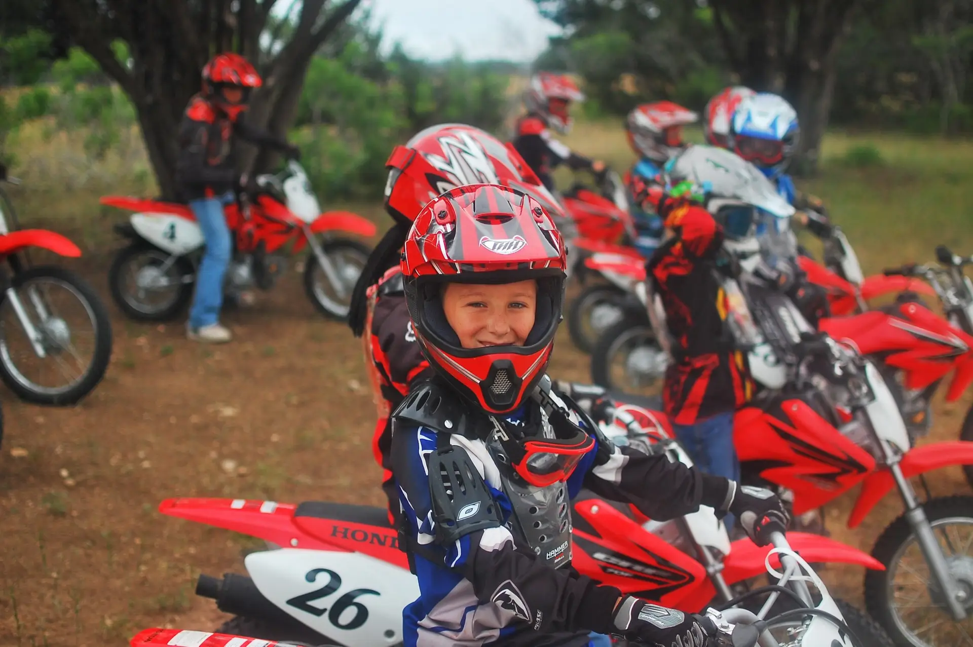 A boy on a red Honda motorcycle at summer camp Iron Horse Country Ranch