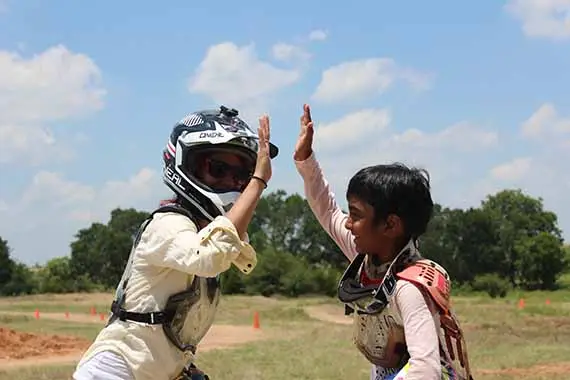 Coach slapping five with camper at Iron Horse Country Motocross Summer Camp