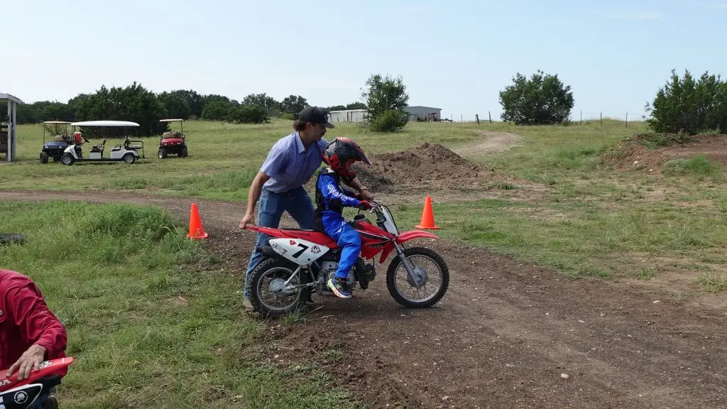 summer camp coach teaching motocross riding to child on Honda 70 at iron horse country ranch summer camp